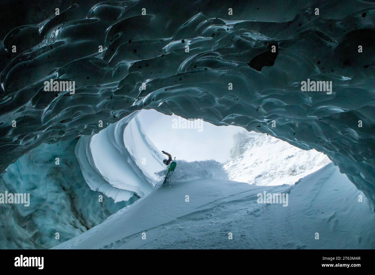 Low angle of unrecognizable skier with ski poles walking in cave at snowy mountain while exploring during vacation at Swiss Alps Stock Photo