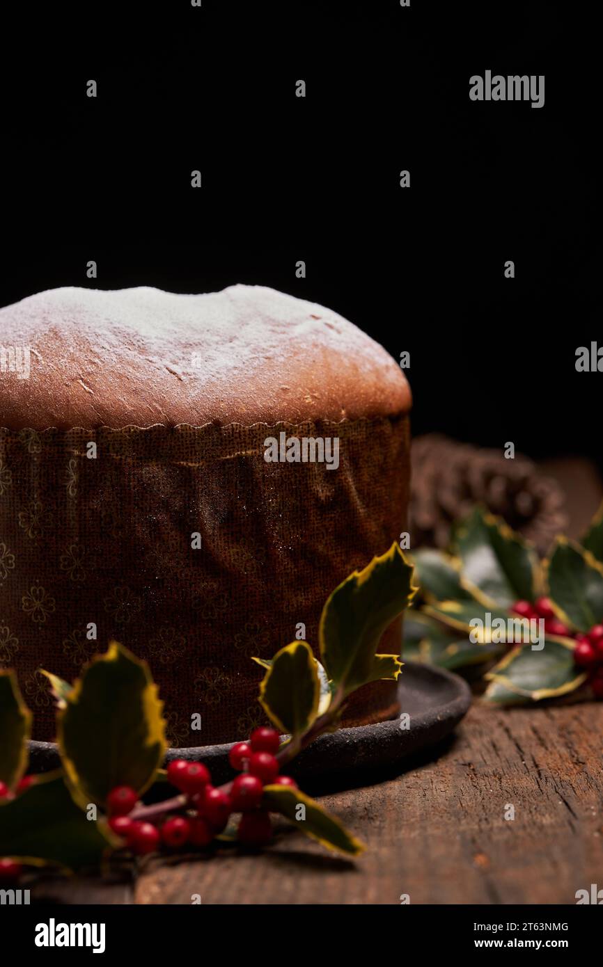 A panettone sprinkled with powdered sugar is complemented by bright red berries and lush green leaves, evoking a festive holiday feel Stock Photo