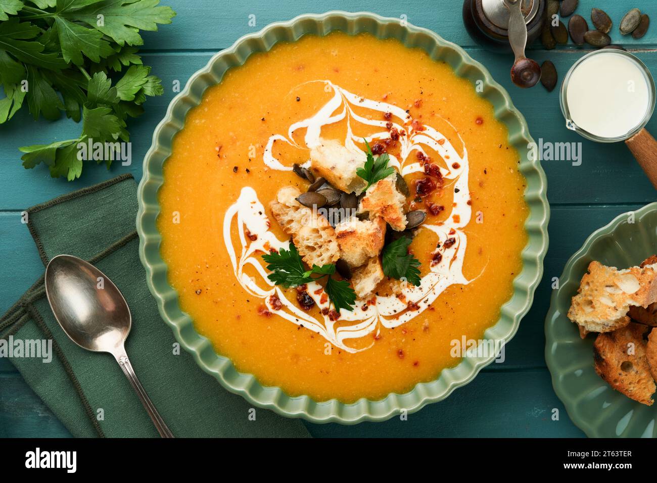 Pumpkin and carrot cream soup with herbs, seasonings and seeds in bowl on dark wooden background in rustic style. Thanksgiving traditional autumn pump Stock Photo