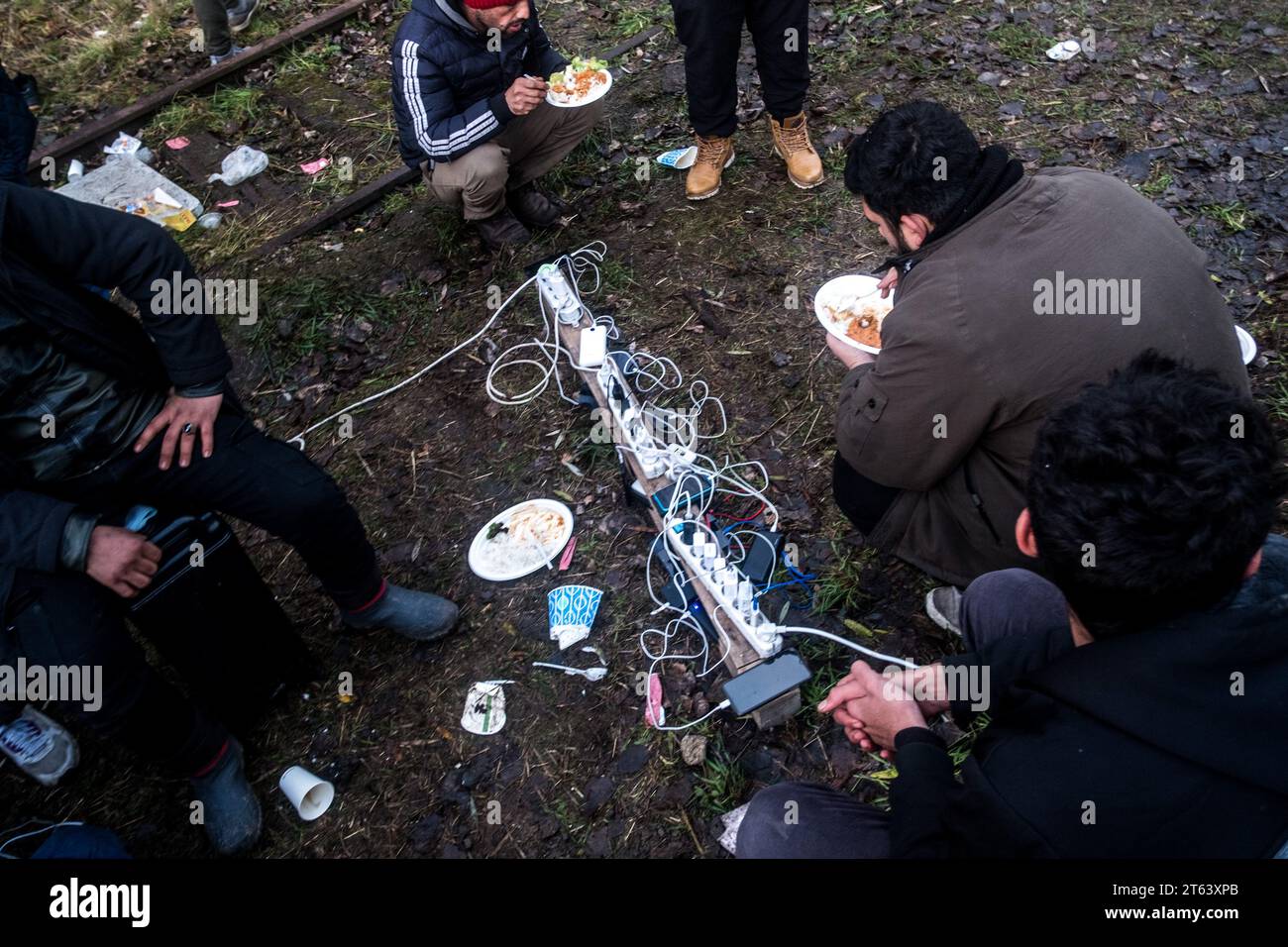 Michael Bunel/Le Pictorium - November 2016, Evacuation of the Calais 'Jungle - 29/11/2021 - France/Haut de France/? Loon Plage ? - Men charging their laptops on power strips connected to a generator brought in by an association. Following the evacuation of the Grande Synthe camp on November 16, a new camp, made up mainly of Kurdish exiles, has been set up near Grande Synthe. November 29, 2021. Loon Plage. France. November 2016, the 'jungle' of Calais, the largest shantytown in Europe, was evacuated. Five years later, the exiles on the road to Great Britain are still there and c Stock Photo