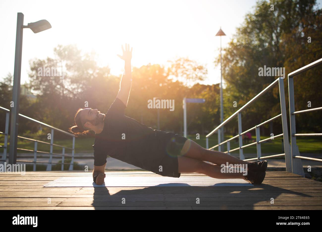 Sporty Young Man Doing Side Plank Exercise While Training Outside Stock Photo
