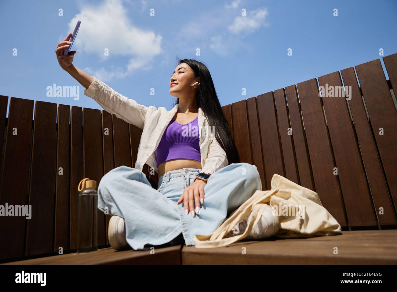 Beautiful Asian female taking a selfie with a modern smartphone while ...