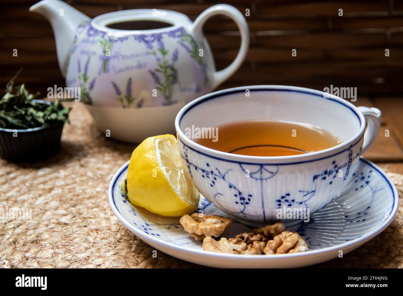 Morning setup on wooden table at balcony, newspapers, cup of natural tea, teapot, organic honey from farm, fresh green tea leaves and organic fruits Stock Photo