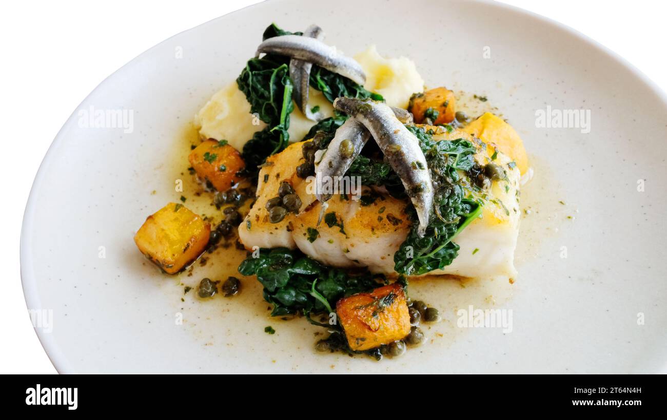 Cooked fillet of cod with anchovies served with cabbage, potato, carrots and capers - John Gollop Stock Photo