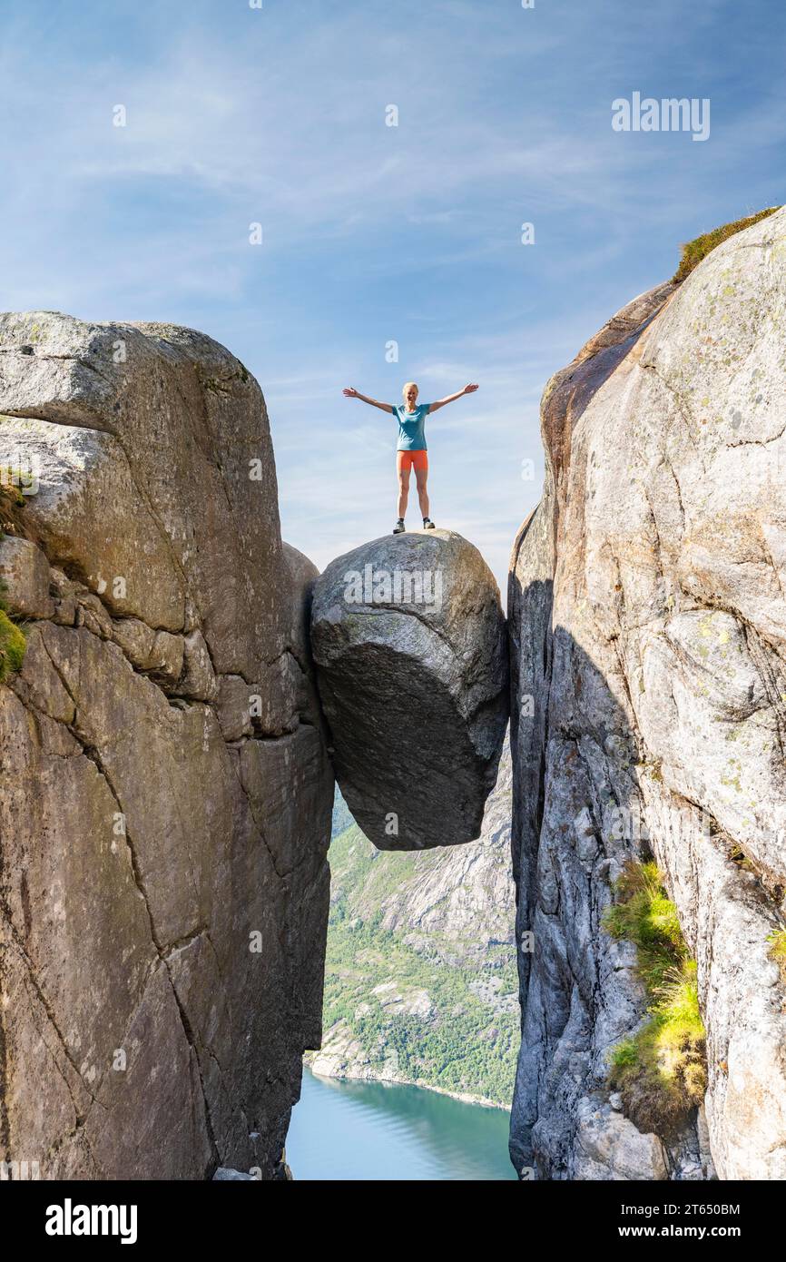 Woman standing onKjeragbolten, jammed rock above the Lysefjord, Kjerag, Lysebotn, Rogaland, Norway Stock Photo