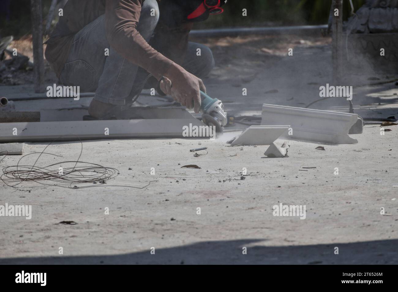 Workers are using grinding stones to cut cement blocks. Causing smoke and dust to cloud over the area Stock Photo