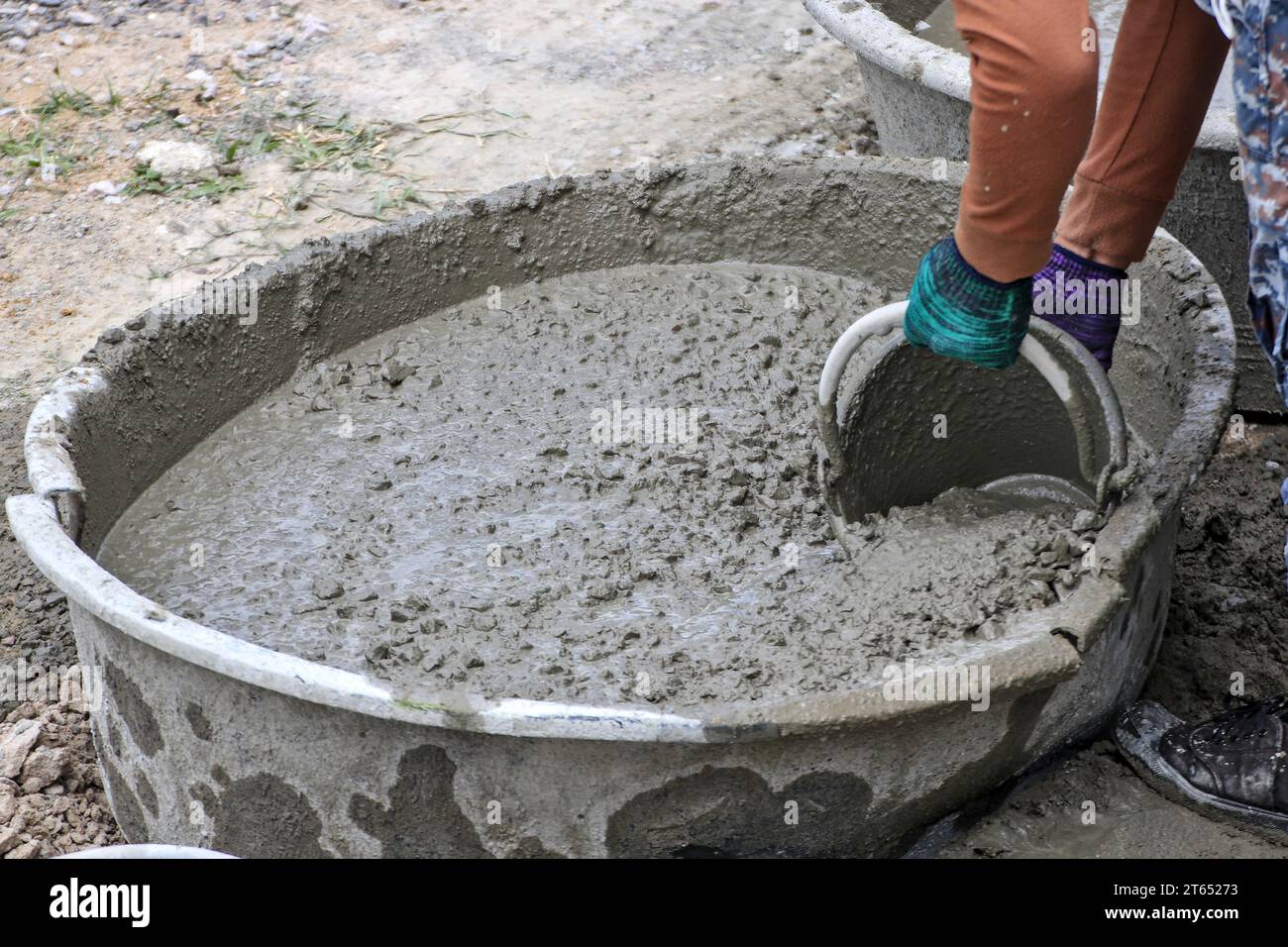 A worker uses a bucket to scoop ready-mixed concrete in construction work on site. Stock Photo