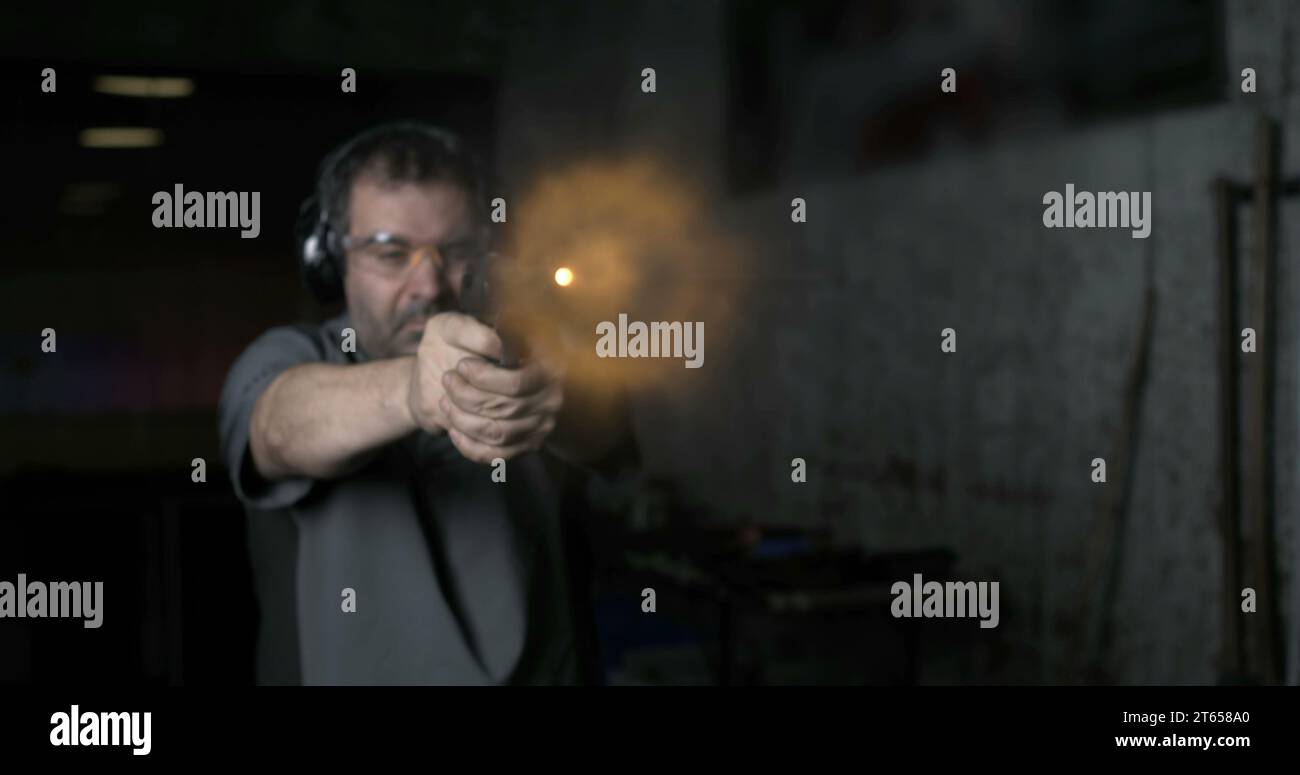 Man aiming and firing with Desert Eagle gun in high-speed slow-motion at 800 fps at shooting range training. Person practicing with weapon Stock Photo