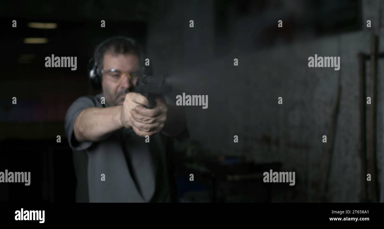 Man aiming and firing with Desert Eagle gun in high-speed slow-motion at 800 fps at shooting range training. Person practicing with weapon Stock Photo