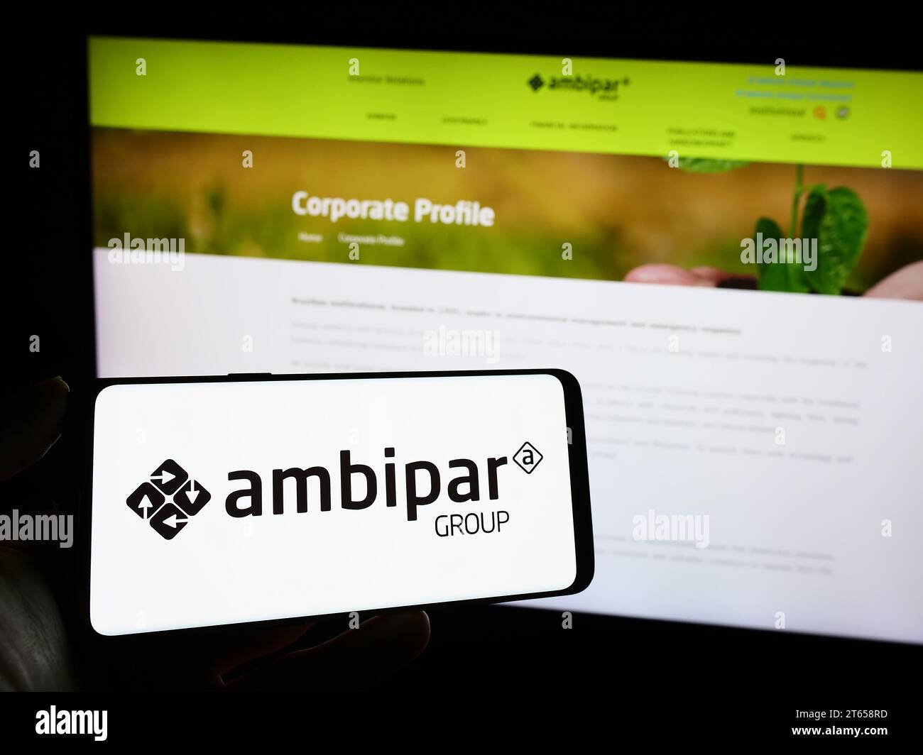 Person holding mobile phone with logo of Brazilian environmental services company Ambipar Group in front of web page. Focus on phone display. Stock Photo
