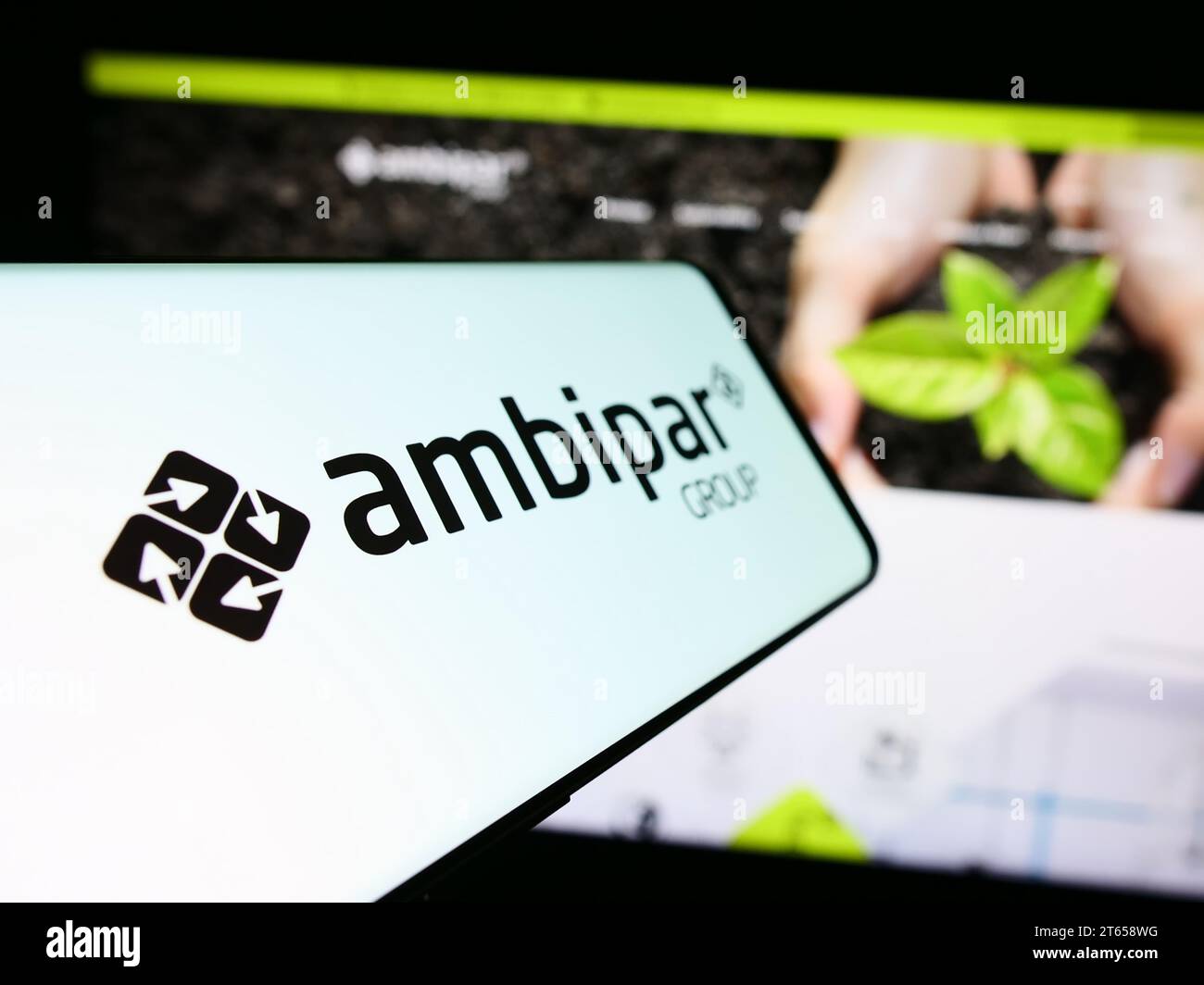 Mobile phone with logo of Brazilian environmental services company Ambipar Group in front of website. Focus on center-left of phone display. Stock Photo