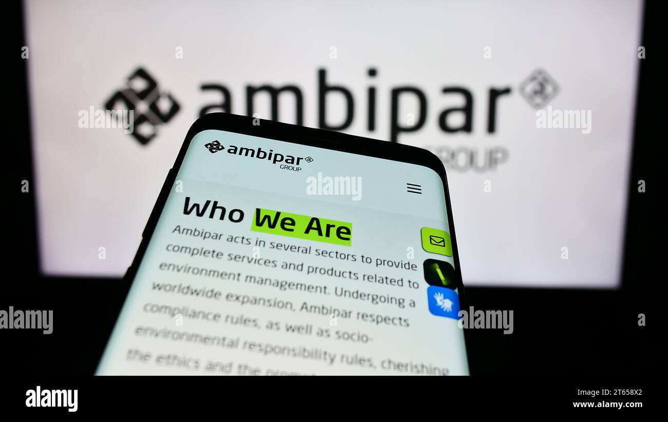 Smartphone with website of Brazilian environmental services company Ambipar Group in front of business logo. Focus on top-left of phone display. Stock Photo