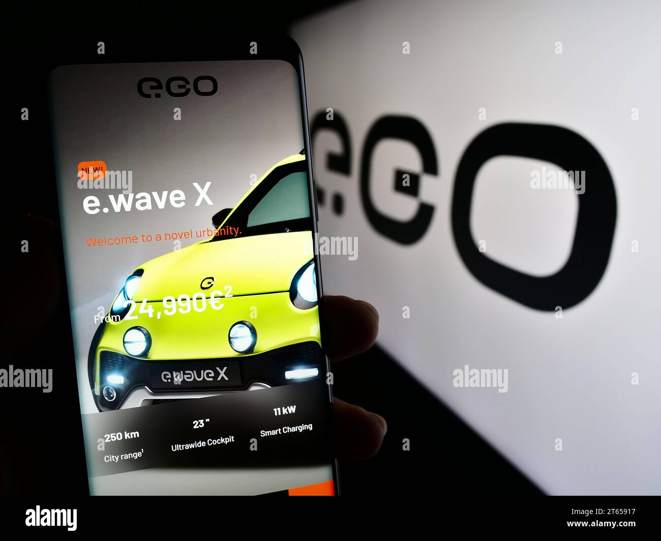 Person holding cellphone with web page of German electric vehicle company Next.e.GO Mobile SE in front of logo. Focus on center of phone display. Stock Photo