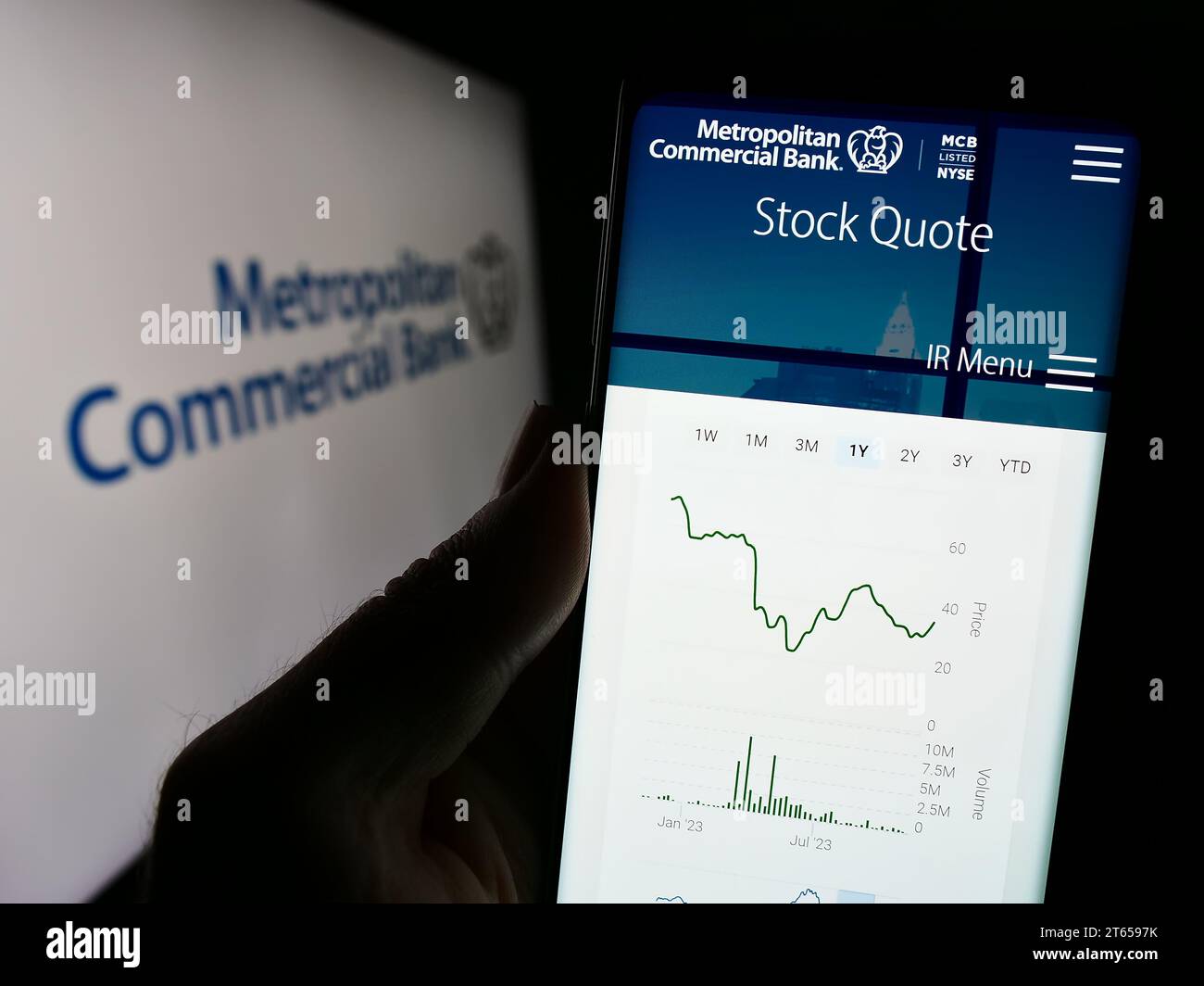 Person holding smartphone with website of US financial company Metropolitan Commercial Bank (MCB) with logo. Focus on center of phone display. Stock Photo
