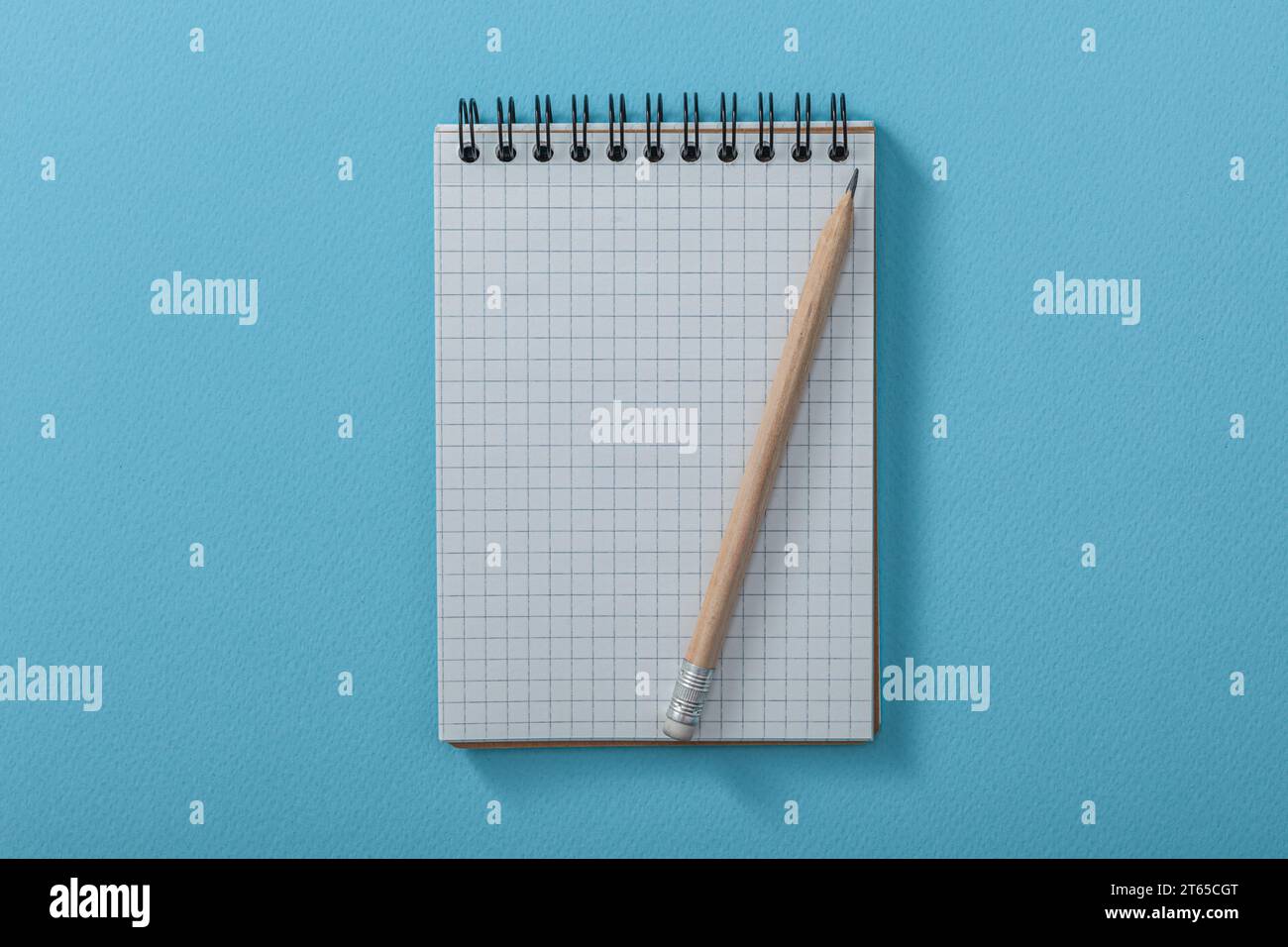 Blank Сheckered Notepad With Wooden Pencil On Blue Background Stock Photo