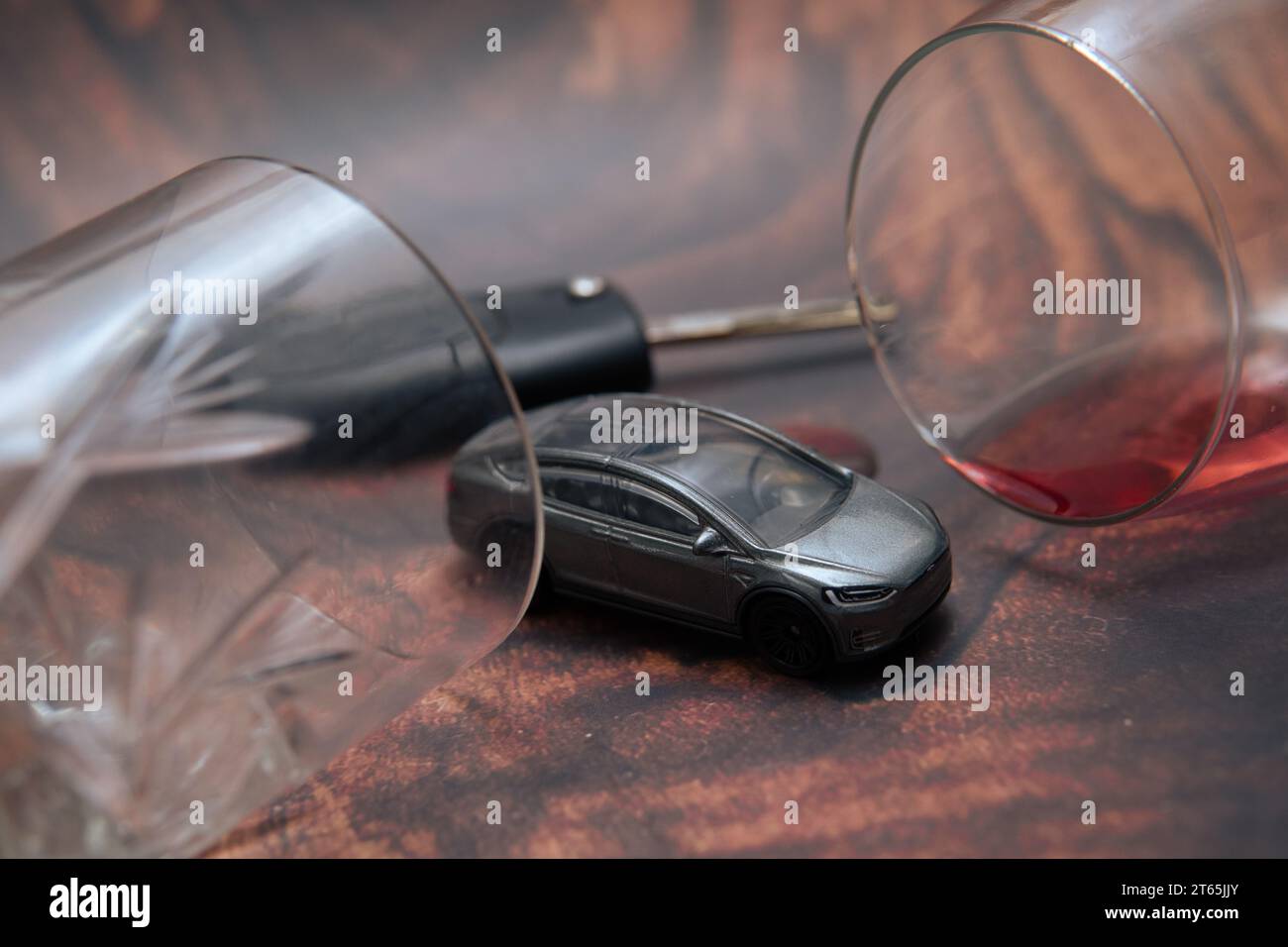 concept showing drunk driving. A toy car next to alcohol glasses