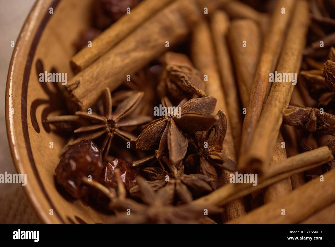 a patterned ceramic bowl filled with whole cinnamon sticks and clove flowers. A mixture for preparing mulled wine. Autumn mood Stock Photo