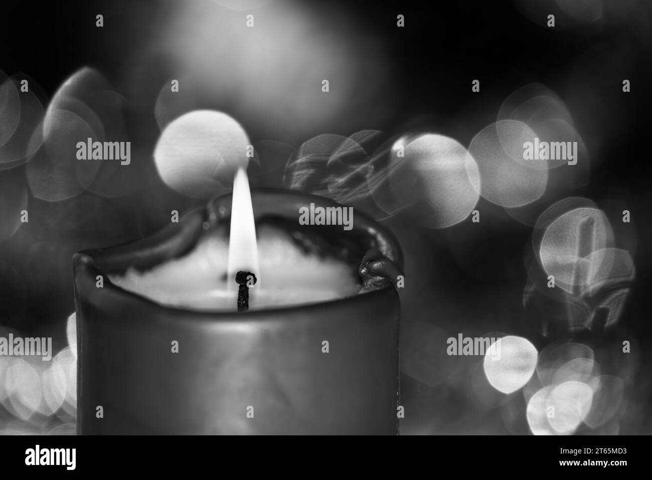 Burning candle against blurred background in black and white colors. Focus on the flame Stock Photo