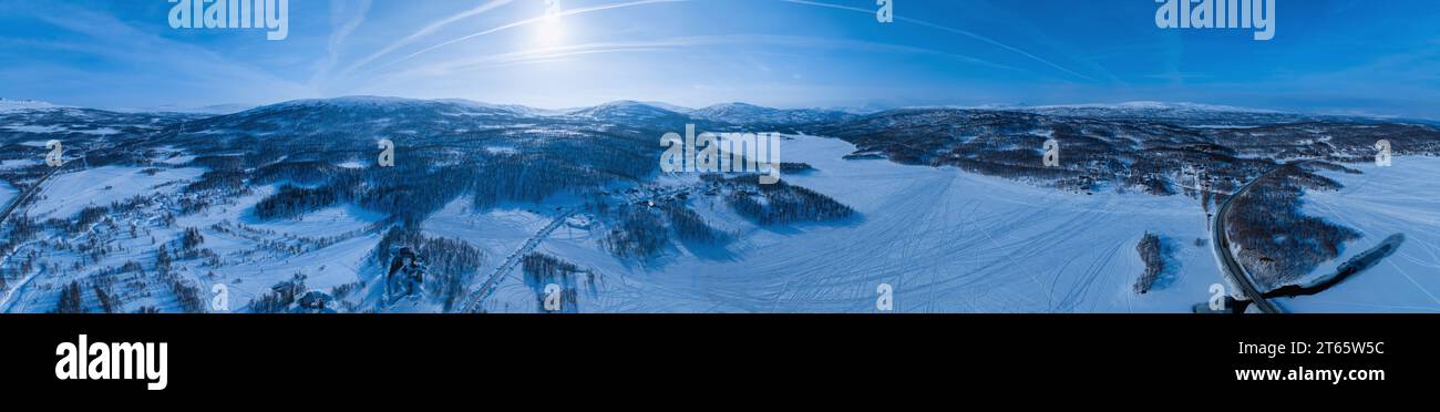 Very wide scenic aerial panorama on frozen lake, mountains with snow mobile traces, sunny blue sky with plane traces, contrails. Scandinavian white wi Stock Photo
