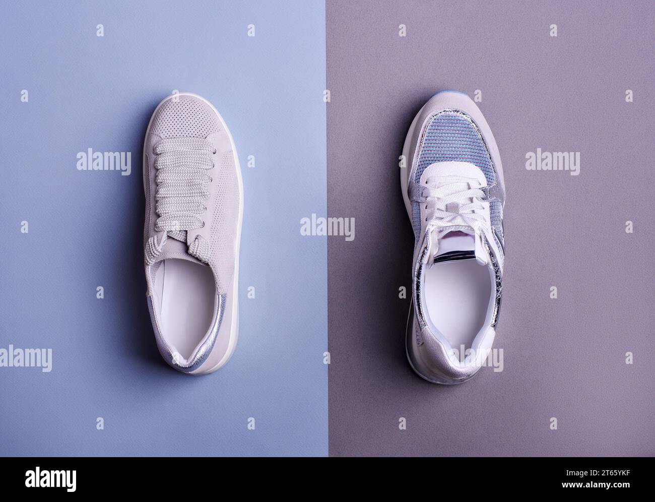 Top view of two stylish different sneakers arranged on a two-color background, gray and blue color scheme. Fashionable sports footwear. Creative minim Stock Photo