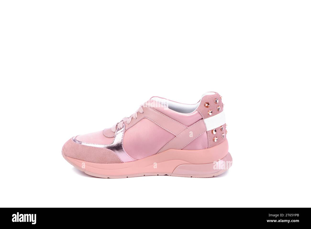 Side view of a stylish women's running shoe made of pink materials of different textures: leather, fabric, and suede. Golden rivets on a counter. Barb Stock Photo