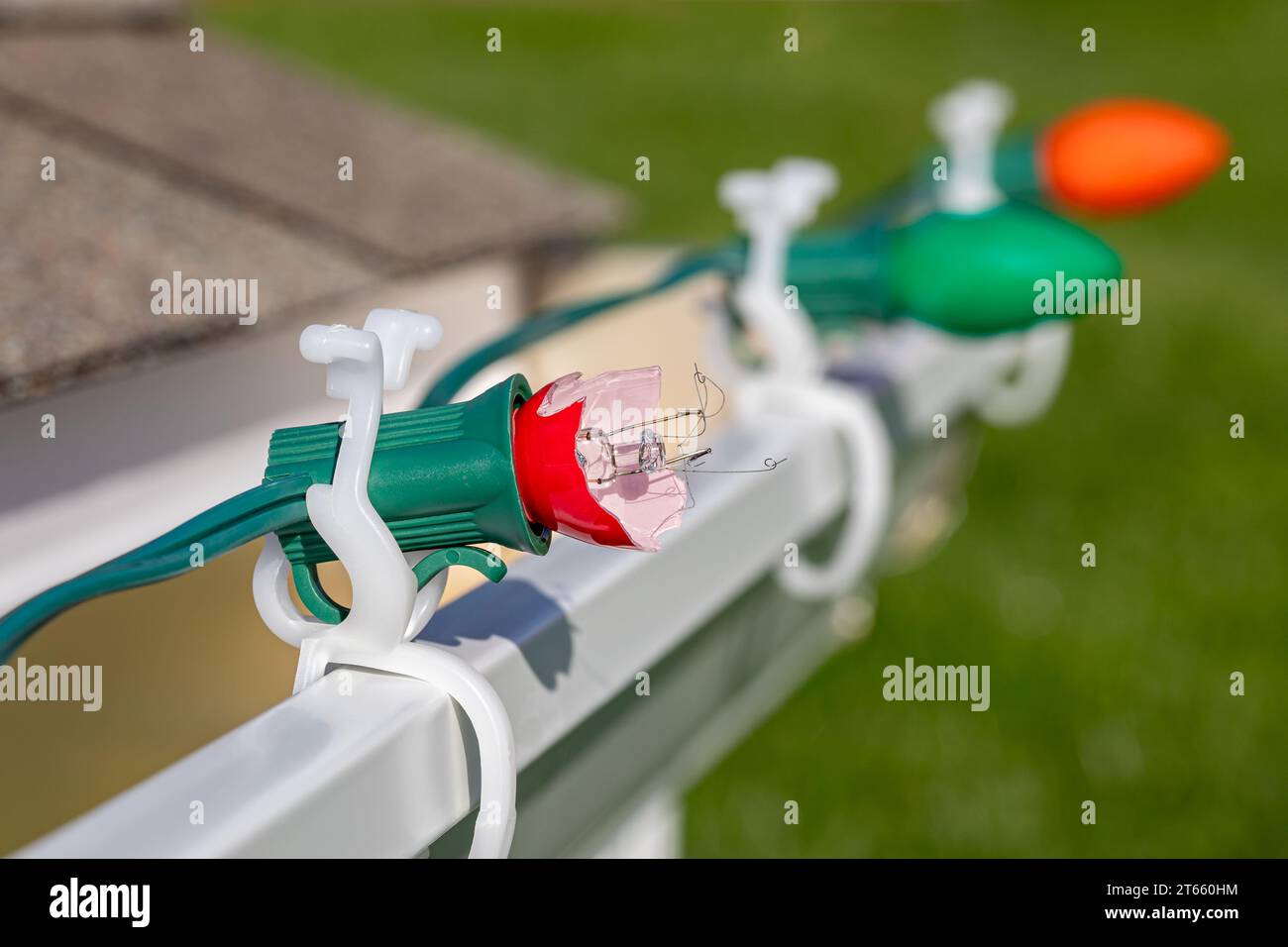 Christmas string lights with broken bulb on gutter of house . Holiday