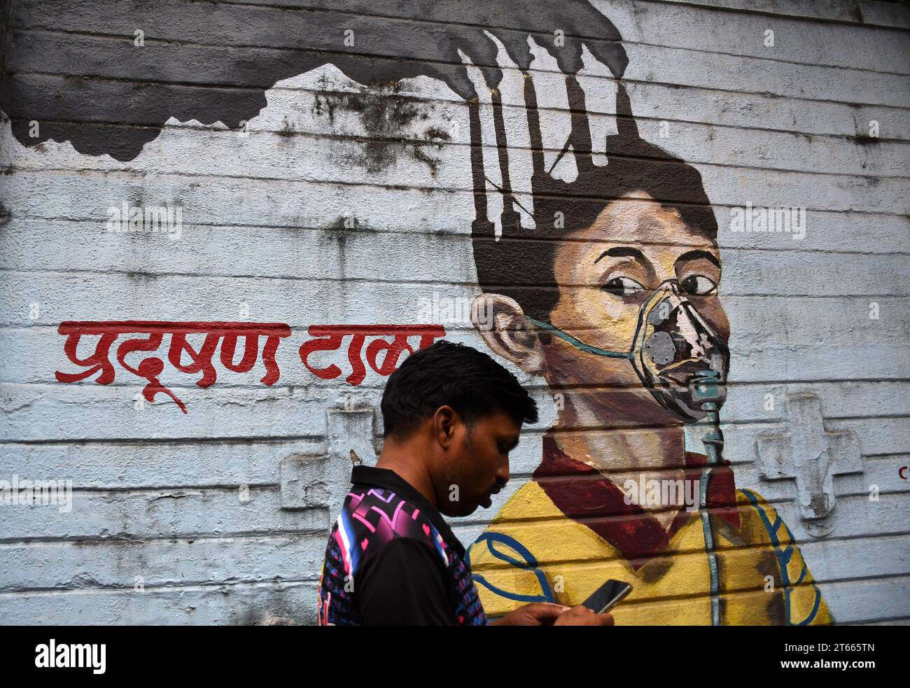 Mumbai, India. 08th Nov, 2023. A man looking at his mobile phone while walking past a mural painted on the wall to create awareness about air pollution in Mumbai. Air pollution in Mumbai is reaching alarming level due to ongoing construction work at more than six thousand site including infrastructure projects which leaves dust suspended in the air, it mixes with the vehicular smoke and other chemical matter suspended in the air to create smog which is harmful to the health of citizens. (Photo by Ashish Vaishnav/SOPA Images/Sipa USA) Credit: Sipa USA/Alamy Live News Stock Photo