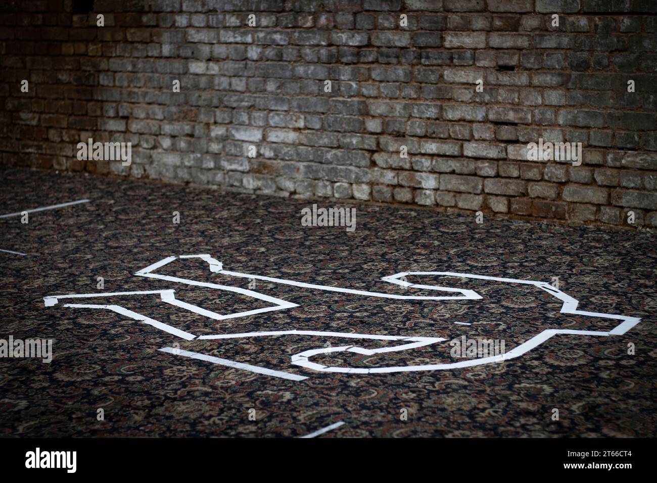 A white tape chalk outline in the shape of a dead body. Stock Photo