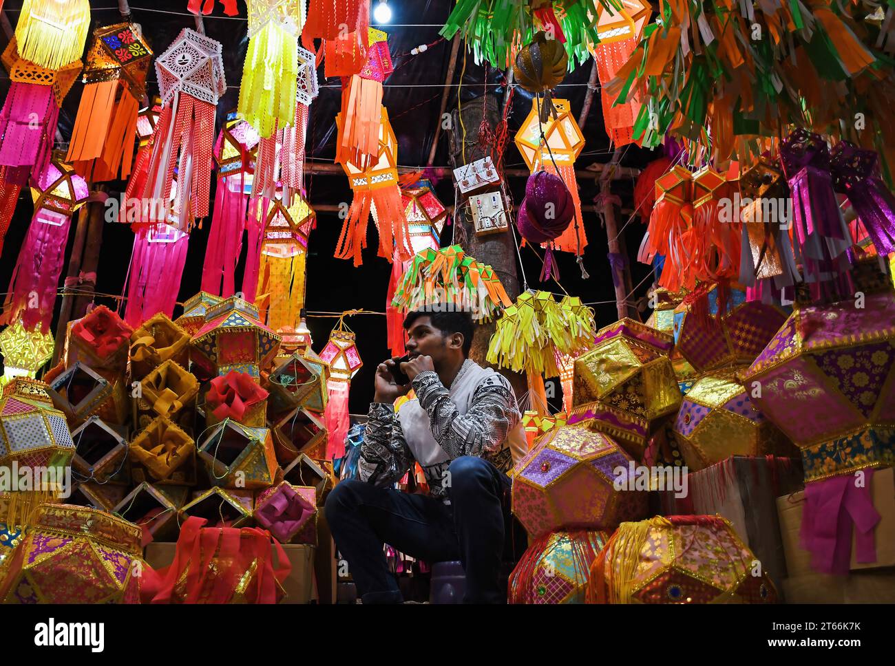 Mumbai, India. 08th Nov, 2023. A shopkeeper speaks on his mobile phone as he awaits customers to sell lanterns ahead of Hindu festival of lights, Diwali in Mumbai. Diwali festival is celebrated by Hindus where they shop for lanterns ahead of the festival, clean their home, prepare sweets and snacks, make rangoli (traditional Indian art form where various designs are made on the floor) and light their homes with earthen lamps marking victory of light over darkness. Credit: SOPA Images Limited/Alamy Live News Stock Photo