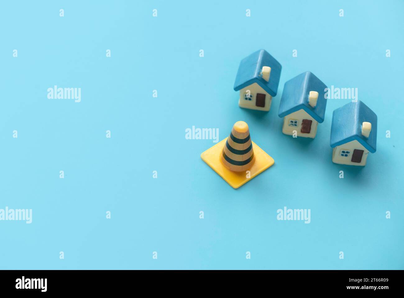 Concept of under construction or fixing for home, property or real estate.Miniature house with traffic cone over a blue background with copy space. Stock Photo