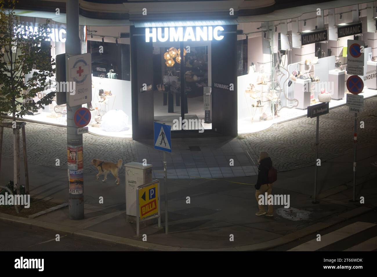 A man and his dog walks in front of the Humanic store, Vienna Austria