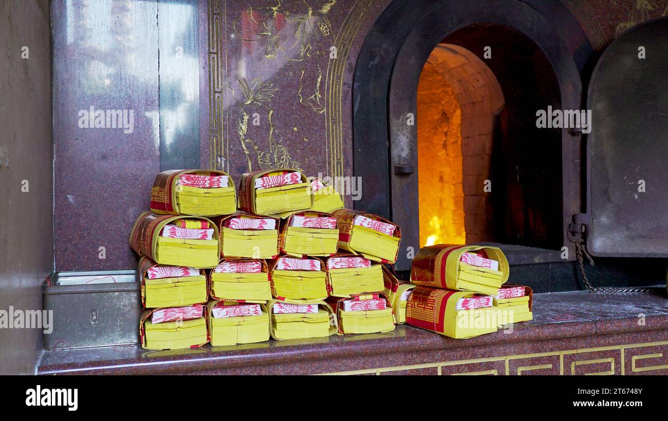 Golden spirit money stacked by the burner, awaiting the ritualistic burning. Joss paper, incense paper, paper money, ghost money, offering money Stock Photo