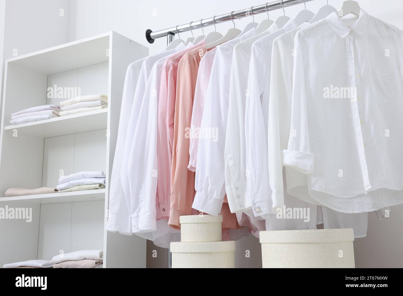 Wardrobe organization. Rack with different stylish clothes shelving unit and boxes near white wall Stock Photo Alamy