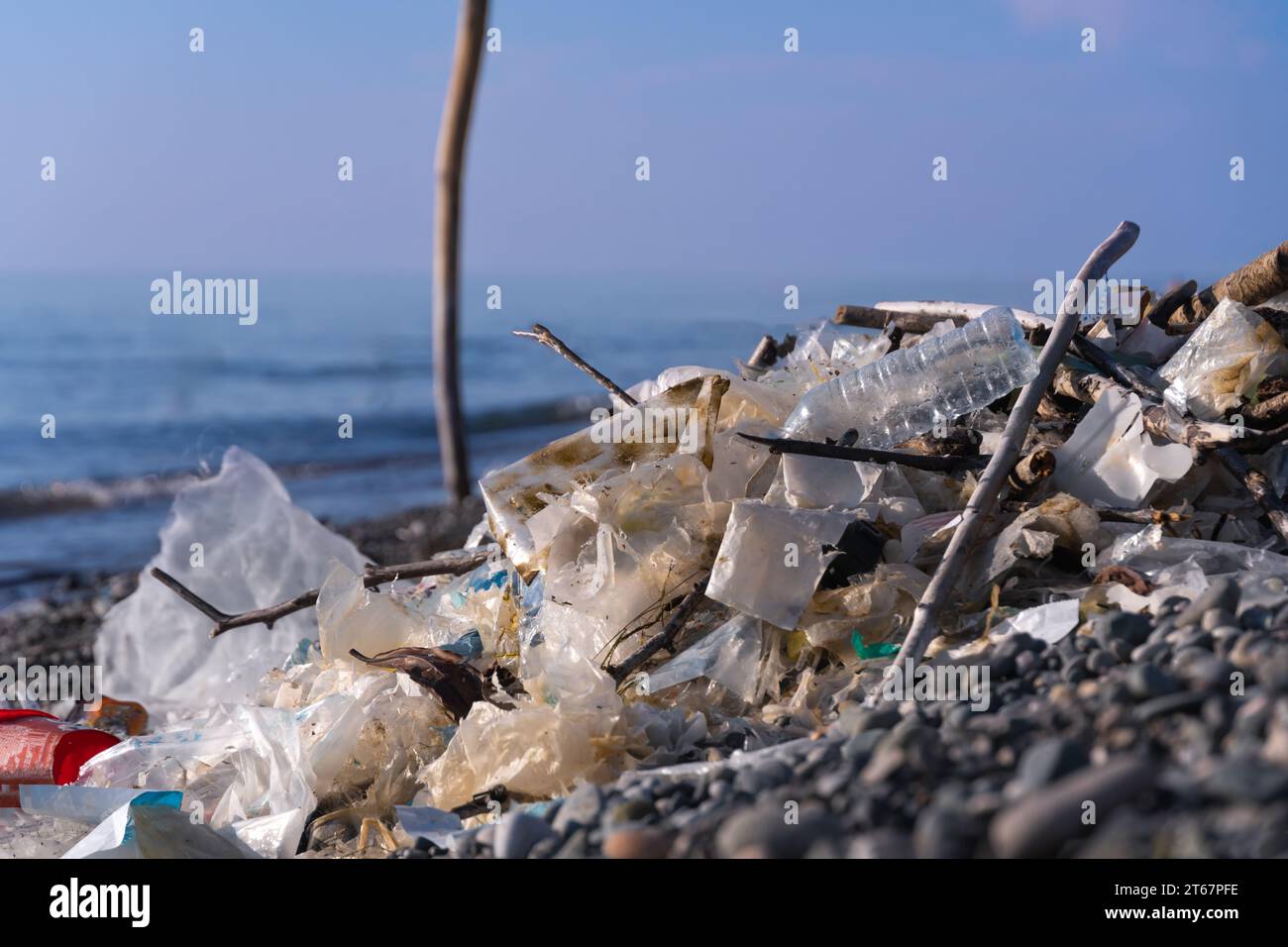 Close-up of a pile of garbage, cellophane on a pebble beach at sea on a sunny day. Concept of environmental pollution, environmental disaster Stock Photo