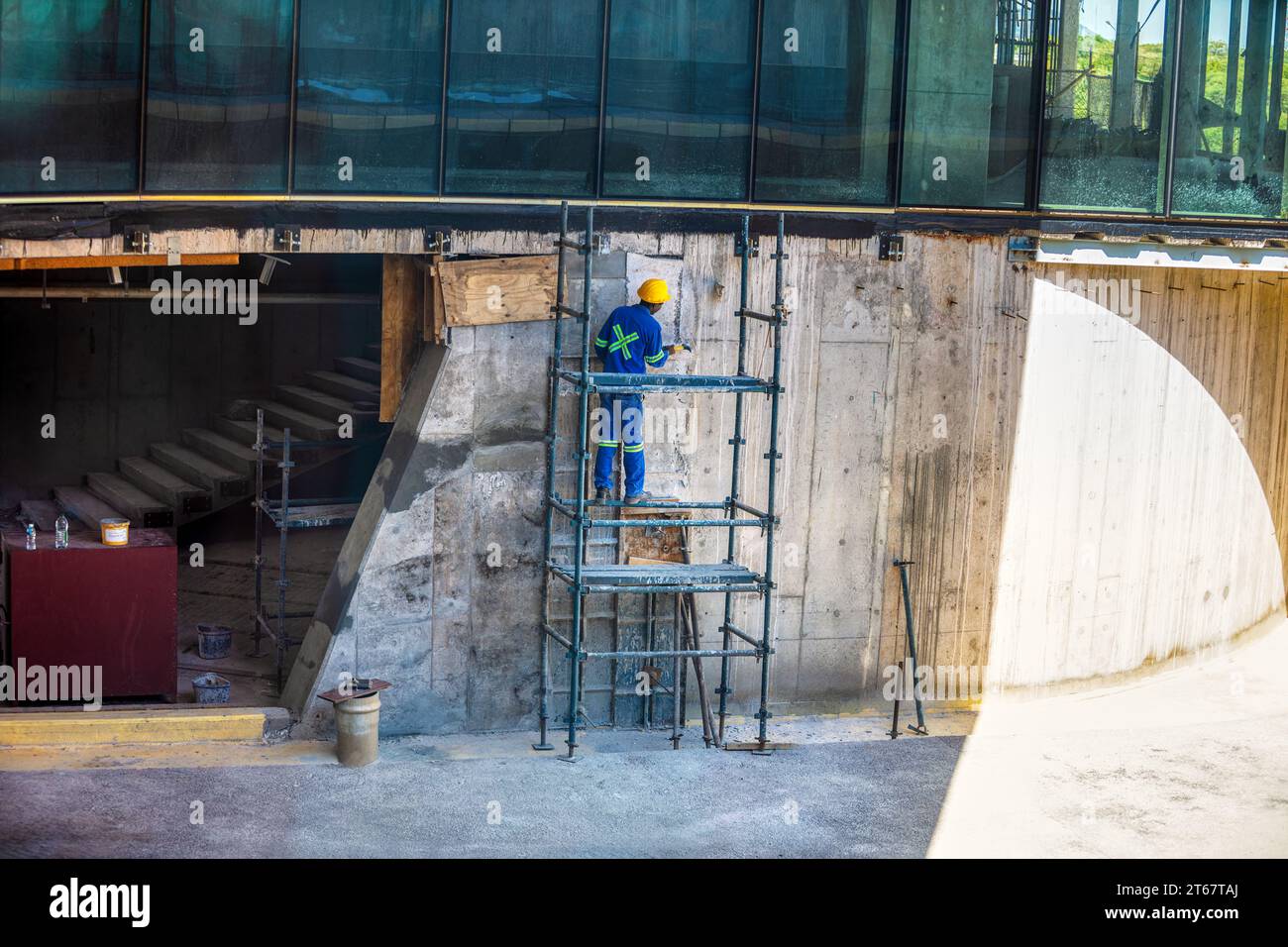 african american construction worker climbed on scaffolding working at a facade on a building Stock Photo