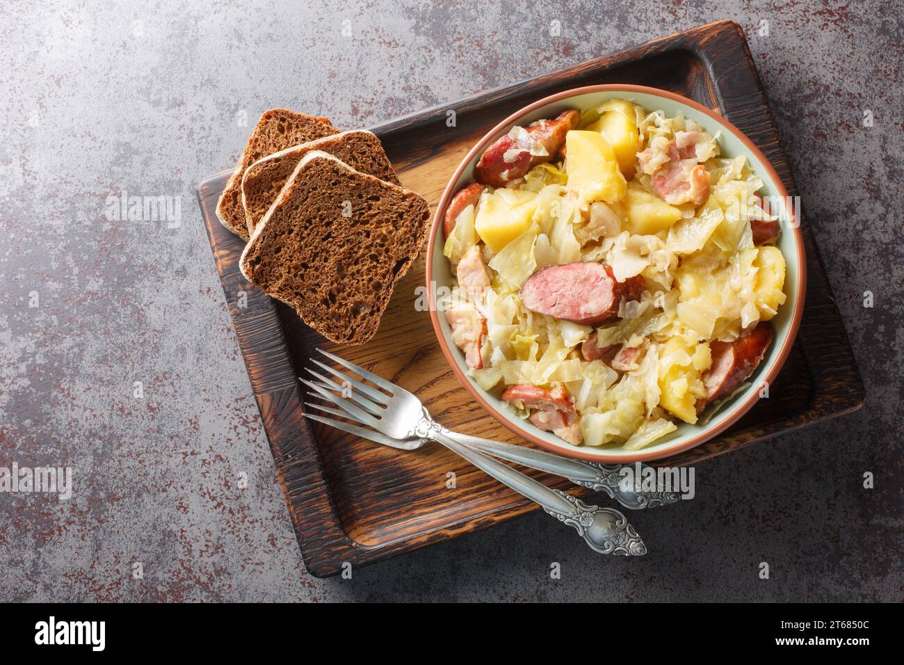 German Hunter Cabbage Stew with potatoes, sausage, bacon and onions close-up in a bowl on the table. Horizontal close-up in a bowl on the table. Horiz Stock Photo