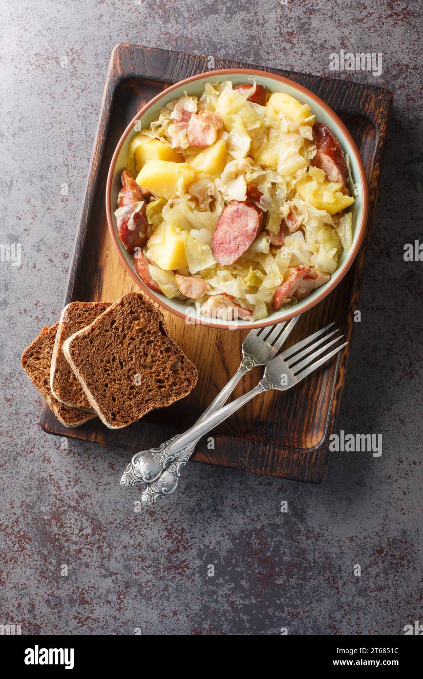 German Jager Kohl, hunter's cabbage with Sausage, Bacon and Potatoes close-up in a bowl on the table. Vertical top view from above Stock Photo