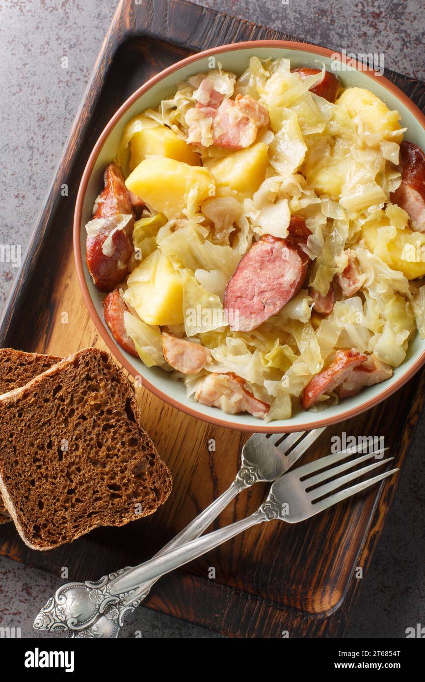 Jager Kohl spicy cabbage stew with potatoes, sausage, bacon and onions close-up in a bowl on the table. Vertical top view from above Stock Photo