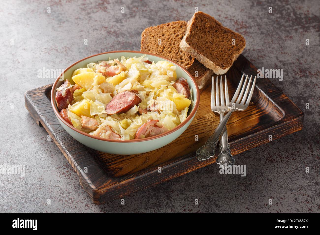 German Hunter Cabbage Stew with potatoes, sausage, bacon and onions close-up in a bowl on the table. Horizontal close-up in a bowl on the table. Horiz Stock Photo