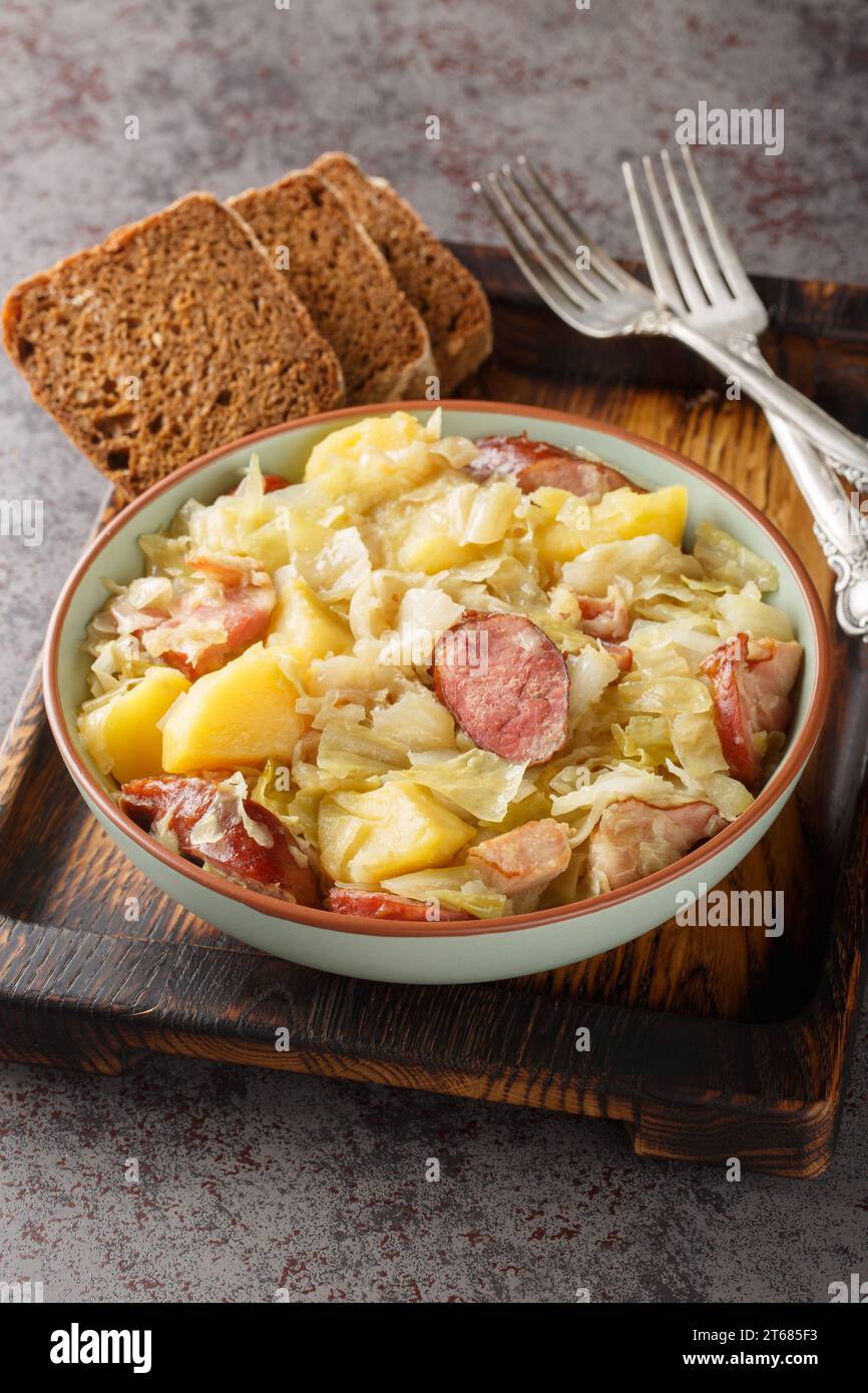 German Jager Kohl, hunter's cabbage with Sausage, Bacon and Potatoes close-up in a bowl on the table. Vertical Stock Photo