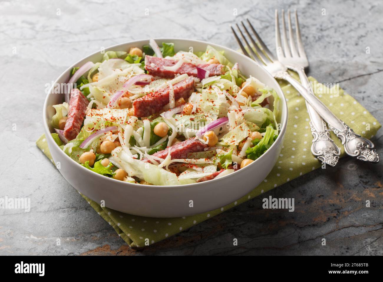 Simple salad combines salami, mozzarella, chickpeas, iceberg lettuce, and romaine, all topped