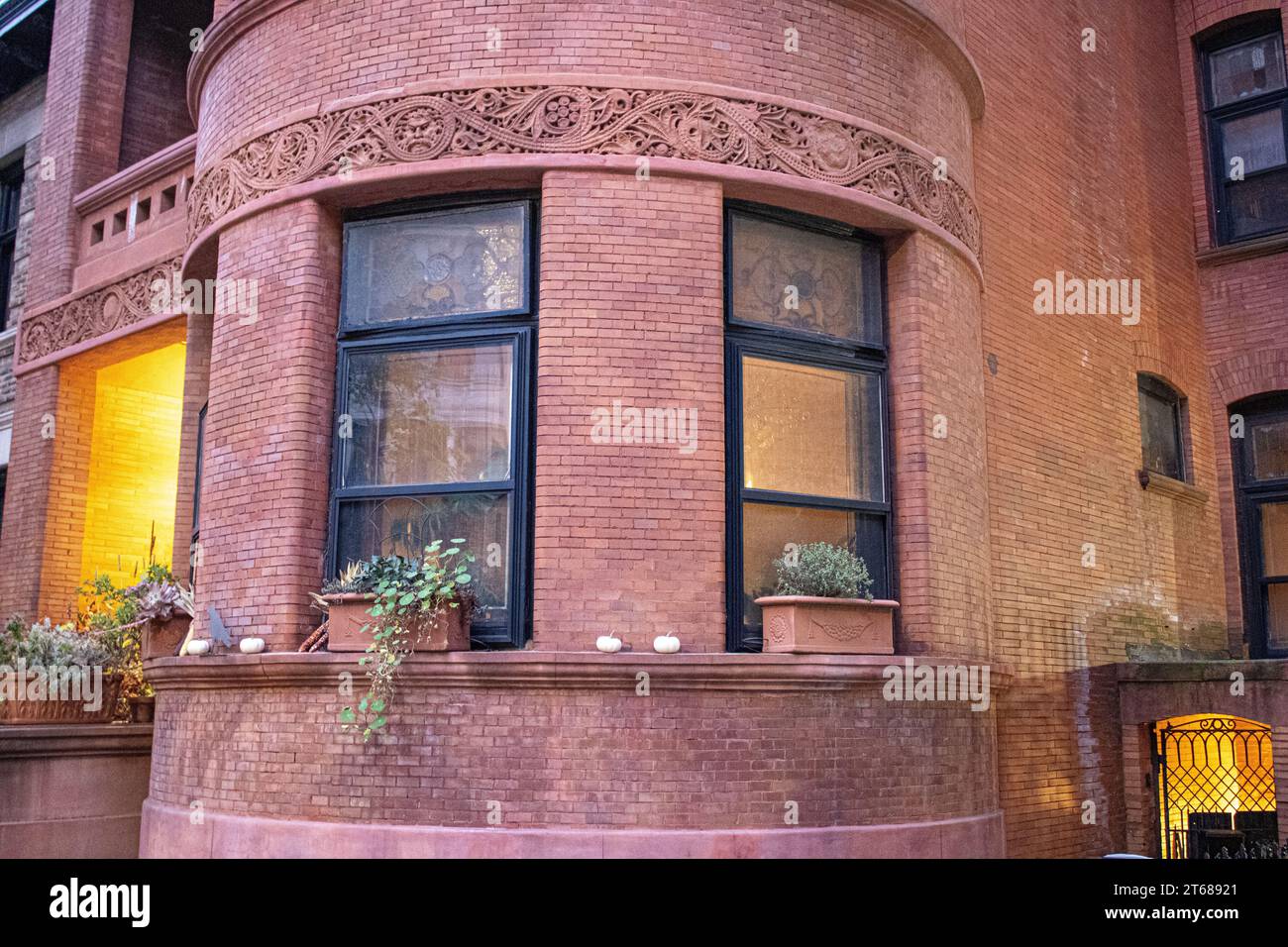 A variety of potted plants are displayed in the window boxes of a house, adding a splash of greenery to the front of the building Stock Photo