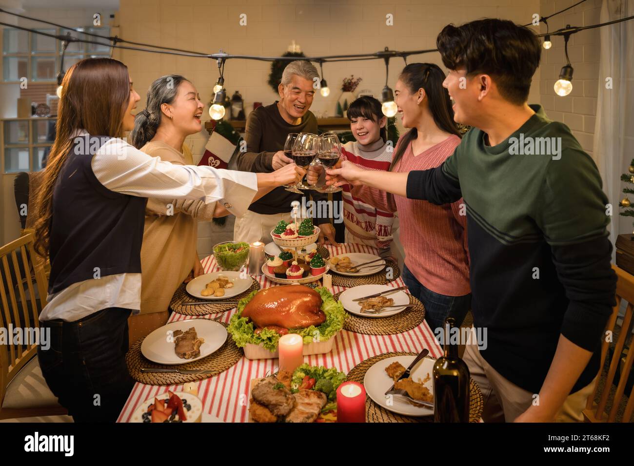An Asian family celebrating Thanksgiving and Christmas with joy and happiness drinking wine Stock Photo