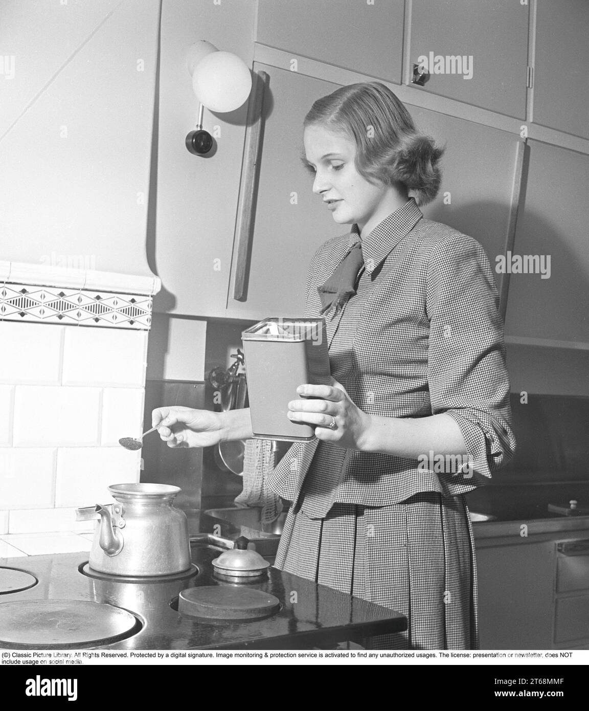 Kitchen in the 1940s. A woman is seen in the kitchen making coffee