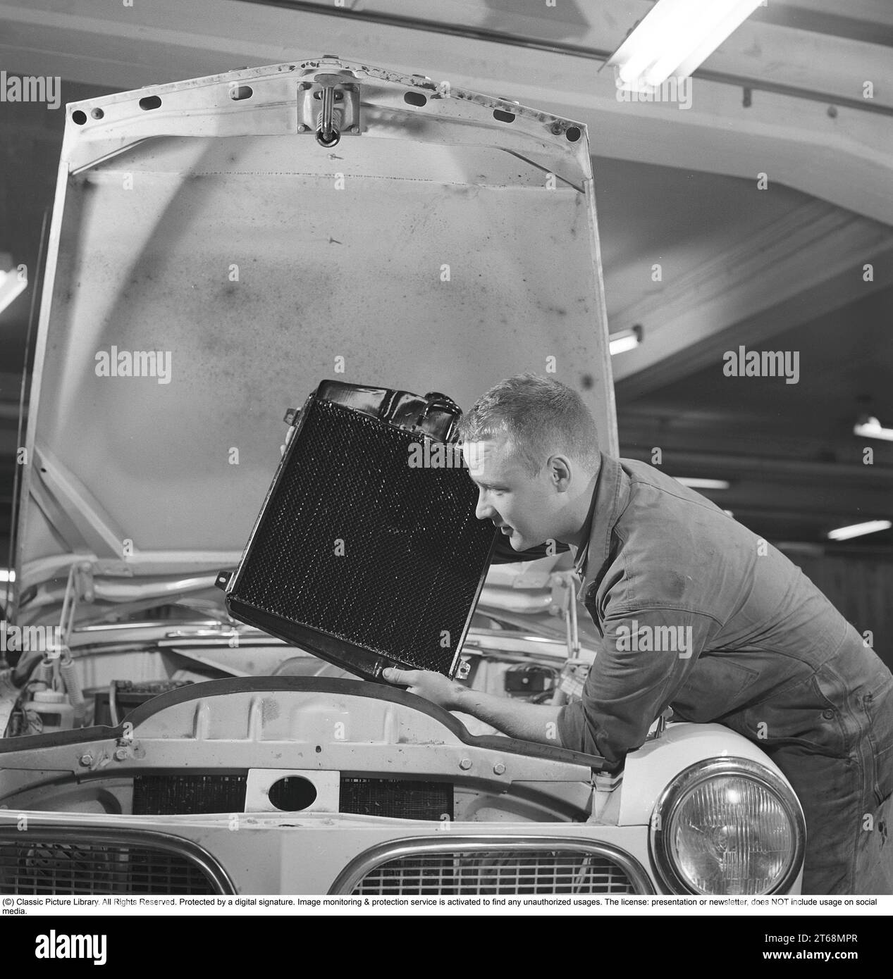 In the 1960s. A mechanic in a garage is about to replace a radiator