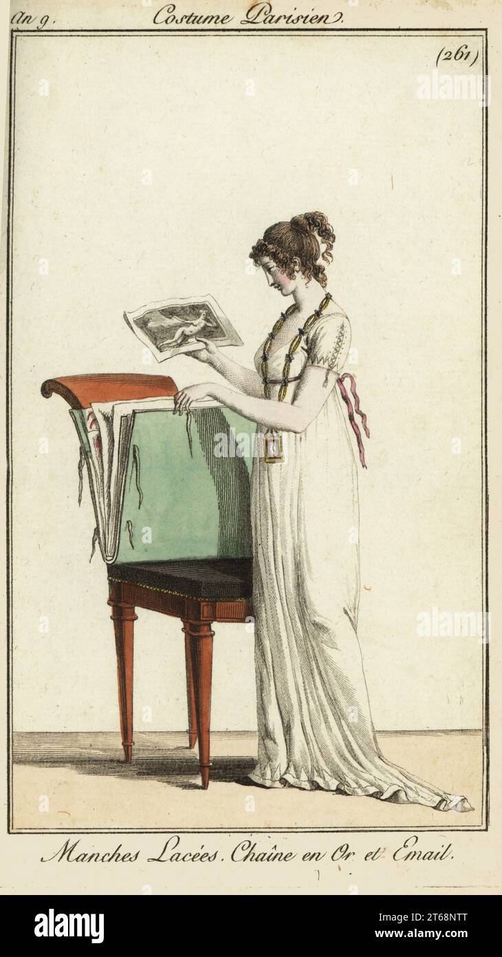 Woman looking at a portfolio of engravings, 1800. She wears a plain dress with laced sleeves and a gold and enamel chain. Manches lacées. Chaîne en Or et émail. Handcoloured copperplate engraving from Pierre de la Mesangeres Journal des Modes et Dames, Paris, 1800. The illustrations in volume 4 were by Carle Vernet, Bosio, Dutailly and Philibert Louis Debucourt. Stock Photo