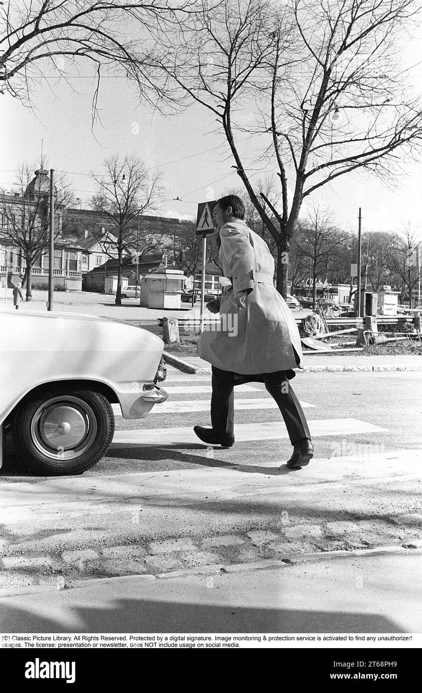 In the 1960s. A moment when a man walks on a pedestrian crossing but a car has not noticed him and keeps driving. The man jumps away from the car to avoid being hit by it. Sweden 1968. Kristoffersson ref 3-57 Stock Photo