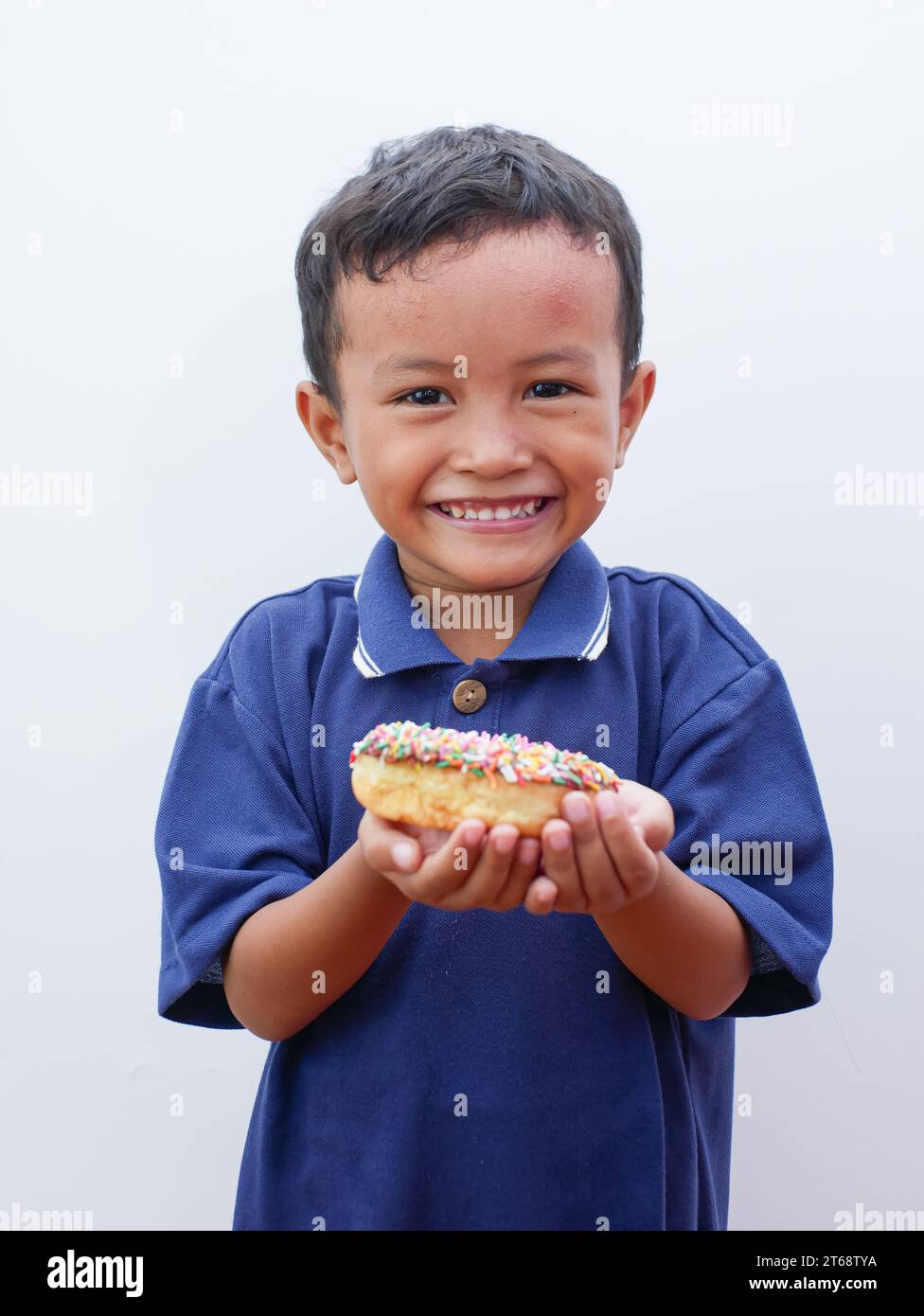 cute little asian boy eating donut isolated on white background Stock Photo