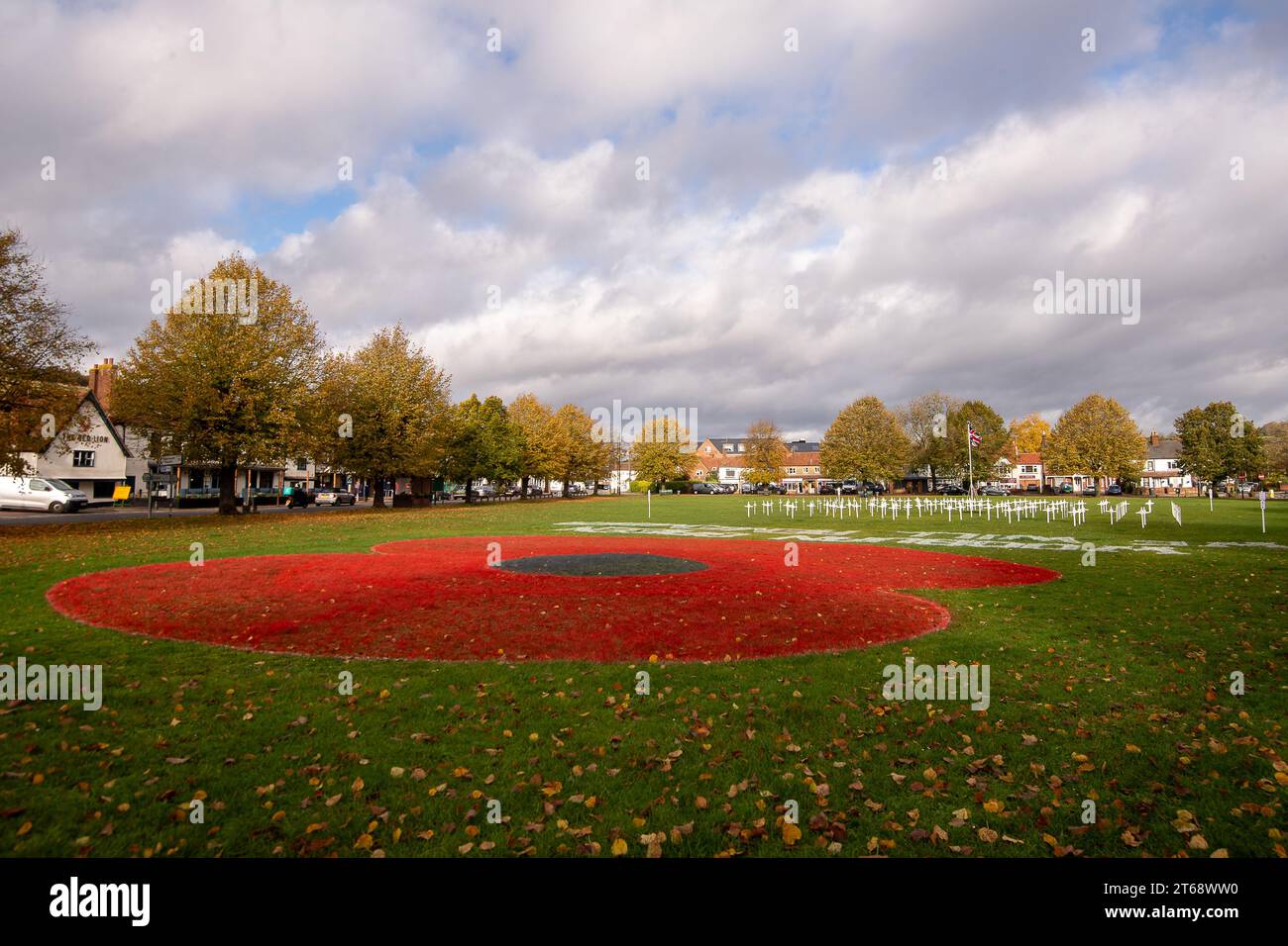 Wooburn Green, UK. 9th November, 2023. A beautiful huge poppy cypher has been painted on the village green in Wooburn Green, Buckinghamshire ahead of Armistice Day and Remembrance Sunday this weekend with the words, Wooburn Green We Will Remember. Taking three hours to complete, the 10 foot poppy was designed and painted by local groundskeeper and contracts manager at Groundtel, Danny Perkins. The 1st Wooburn Scouts have also placed 146 memorial crosses next to the poppy in memory of local villagers who died during WWI and WWII. Credit: Maureen McLean/Alamy Live News Stock Photo