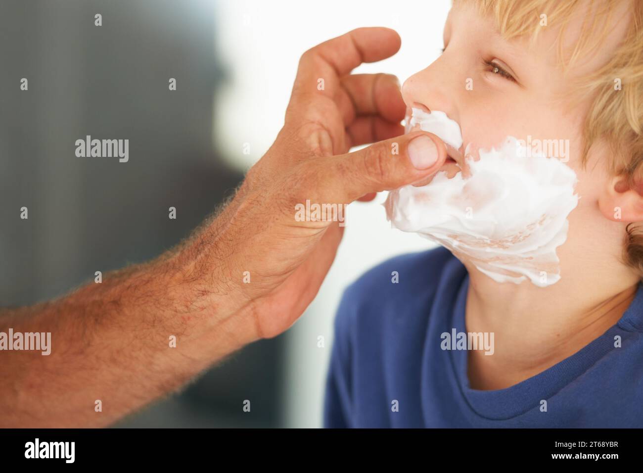Showing him the ropes of shaving. A father playfully putting shaving